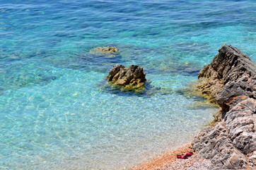 Fototapeta na wymiar beach with clear water and red slippers