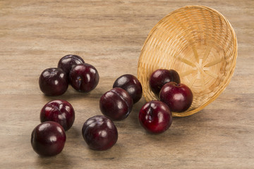 Fresh bright plums in the bowl on board