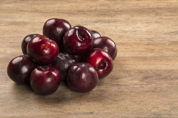 Fresh bright plums in the bowl on board