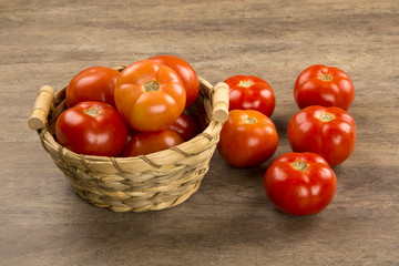 Some tomatoes over a wooden surface on a tomato field as backgro