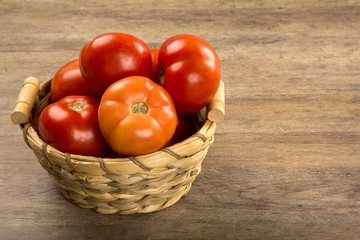 Some tomatoes over a wooden surface on a tomato field as backgro