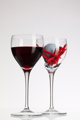 Wine glasses with red wine and golf ball