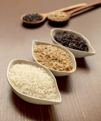 Rice in ceramic container on wood background