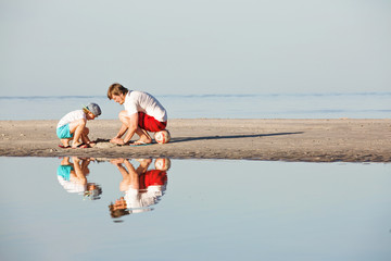 Happy father and son having great time on the beach in sunset