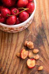 Ripe organic homegrown cherries and stones in a vintage ceramic bowl, on wooden background