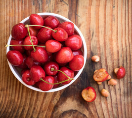 Ripe organic homegrown cherries and stones in a vintage ceramic bowl, on wooden background