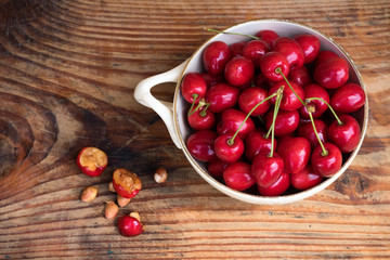 Ripe organic homegrown cherries and stones in a vintage ceramic bowl, on wooden background