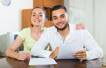 Happy couple with documents indoors.