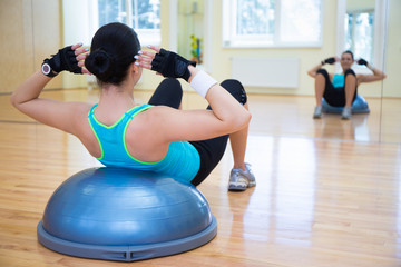young woman doing exercises on bosu ball