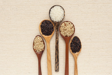Wooden spoon and raw rice with space on background