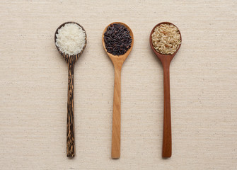 Wooden spoon set with rice on canvas background