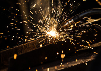 Welder in action with bright sparks. Construction and manufacturing theme. - obrazy, fototapety, plakaty