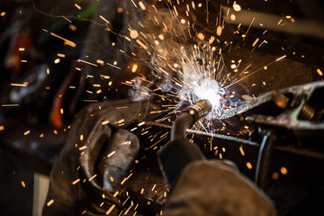 Welder in action with bright sparks. Construction and manufacturing theme. - obrazy, fototapety, plakaty