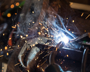Naklejka na ściany i meble Welder in action with bright sparks. Construction and manufacturing theme.