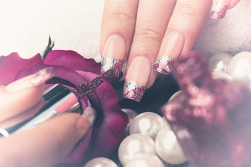 Manicure - Beauty treatment photo of nice manicured woman fingernails. Very nice feminine nail art with silver and purple glitter nail polish. Processed in retro, vintage colors.