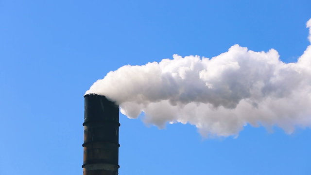 Polluting factory emitting dirty smoke against clear blue sky