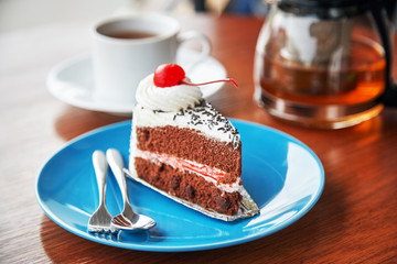 slice of chocolate cake with white icing and cherry
