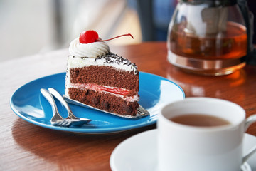 slice of chocolate cake with white icing and cherry