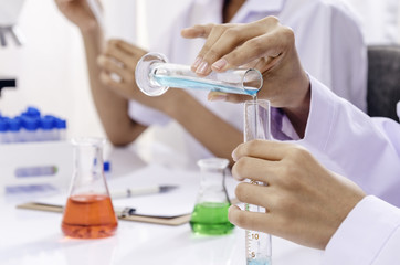 laboratory workers experimenting different liquid in flask containers