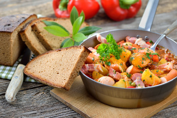 Deftiges Kartoffelgulasch mit Speck und Wiener Würstchen