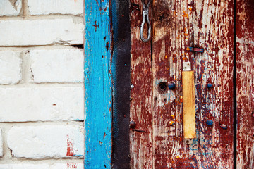 A wooden vintage scaled red door with handle and blue aperture 