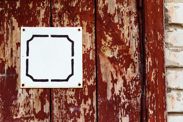 Closeup image of red wooden rusty door with white blank plate 