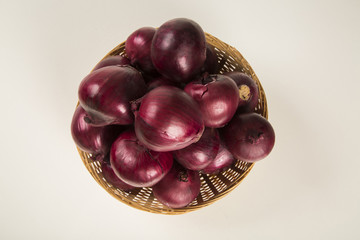 A close-up of red onions in a basket over a table.
