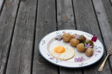 Fried egg with cooked potatoes on a white plate.