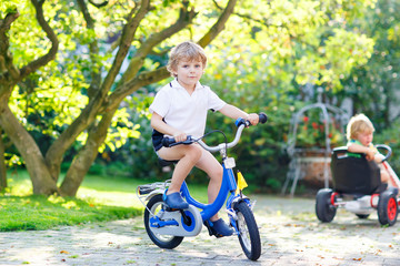 Fototapeta na wymiar Little preschool kid boy riding with bicycle in summer