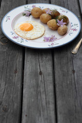 Fried egg with cooked potatoes on a white plate.