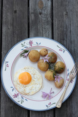 Fried egg with cooked potatoes on a white plate.