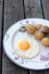 Fried egg with cooked potatoes on a white plate.