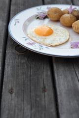Fried egg with cooked potatoes on a white plate.