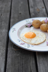 Fried egg with cooked potatoes on a white plate.