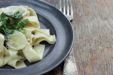 Pappardelle with white clamshells in white sauce.