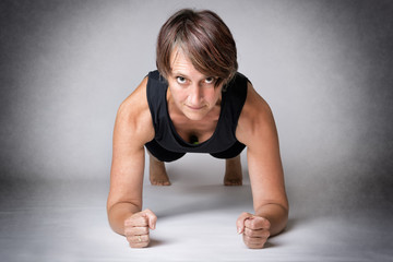 Fototapeta na wymiar Middle aged woman forearm push-ups