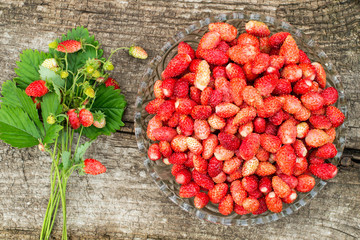 The large glass bowl of ripe strawberries and a bouquet with ber