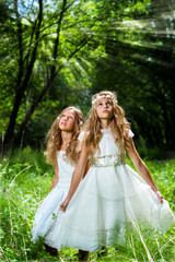 Litte princesses wearing white dresses in woods.