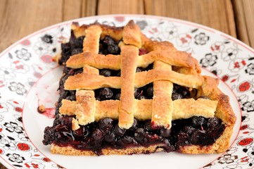 Piece of triangular homemade lattice pie with whole wild blueber