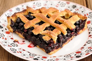 Piece of triangular homemade lattice pie with whole wild blueber