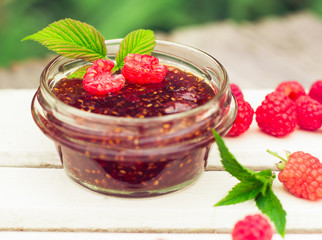 raspberry jam in a jar and fresh berries on the wooden table