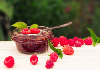 raspberry jam in a jar and fresh berries on the wooden table