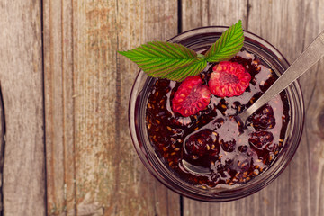 raspberry jam in a jar and fresh berries on the wooden table