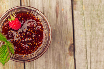 raspberry jam in a jar and fresh berries on the wooden table