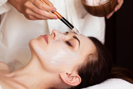Spa treatment. Beautiful woman with facial mask at beauty salon.