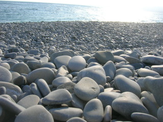 Obraz premium Closeup of white pebbles on the beach on a late sunny afternoon, low angle perspective.