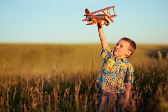 small boy playing with plane on meadow