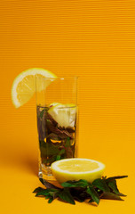Mojito cocktail with lemon and mint on yellow background