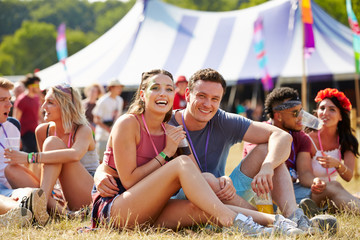 Couple sitting on grass in the audience at a music festival