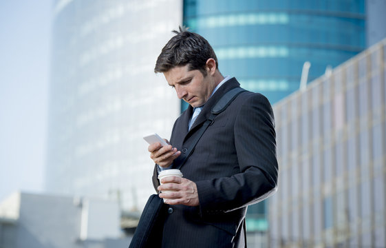 attractive businessman checking text message on mobile phone outdoors